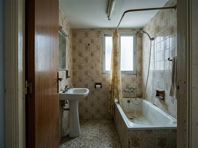 Antes: baño de 1984 con bañera esmaltada, azulejo beige decorado y lavabo de pie